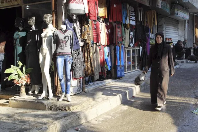A woman walks past clothes shops with mannequins with covered faces in Aleppo January 22, 2015. (Photo by Jalal Al-Mamo/Reuters)