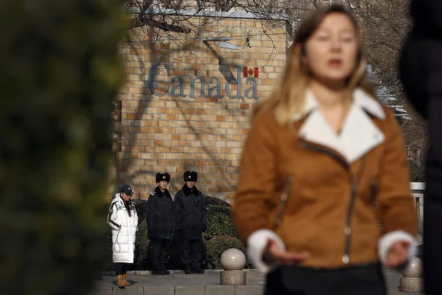 Policemen watch as a journalist reports near the Canadian Embassy in Beijing, Friday, December 14, 2018. Canada is being battered by diplomatic ill winds. First, President Donald Trump attacked Canada on trade. Then Saudi Arabia punished it for speaking up for human rights. Now China has the country in its cross-hairs, detaining two Canadians in apparent retaliation for the arrest of a top Chinese tech executive on behalf of the U.S. Canada's normally reliable ally to the south has left it high and dry. (Photo by Andy Wong/AP Photo)