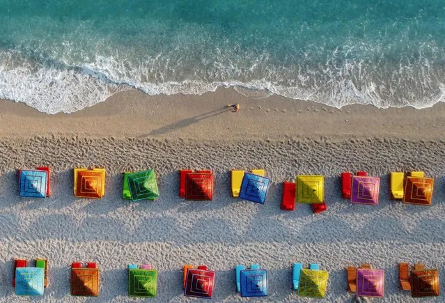 An aerial view shows a person walking near parasols on a beach of the Ionian Sea in Dhermi, Albania, June 20, 2021. (Photo by Florion Goga/Reuters)