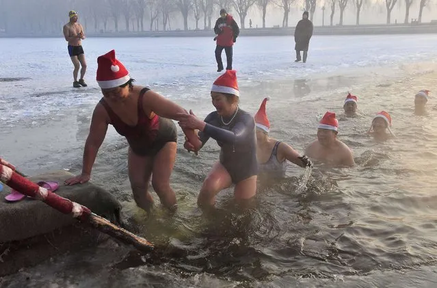 Winter swimmers wearing Santa Claus hats get out of a partially frozen lake after swimming in icy water to celebrate Christmas at a park in Shenyang, Liaoning province December 24, 2013. (Photo by Reuters/Stringer)