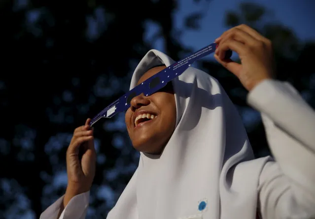 A school girl watches a partial solar eclipse at the Planetarium in Kuala Lumpur, Malaysia, March 9, 2016. (Photo by Olivia Harris/Reuters)