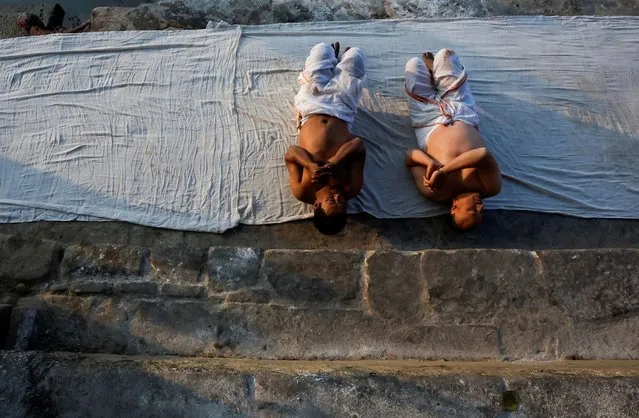 Devotees offer prayer by rolling on the ground during the month-long Swasthani Brata Katha festival at the bank of Hanumante river in Bhaktapur, Nepal on January 29, 2024. (Photo by Navesh Chitrakar/Reuters)