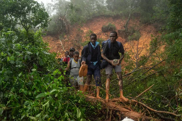School students of St. Charles Luanga, rescued by members of the Zimbabwe Military, walk past a mudslide on March 17, 2019, covering a major road at Skyline junction in Chimanimani, Manicaland Province, Zimbabwe, after tropical cyclone Idai barrelled across the southern African nations with flash floods and ferocious winds. A cyclone that ripped across Mozambique and Zimbabwe has killed at least 162 people. (Photo by Zinyange Auntony/AFP Photo)