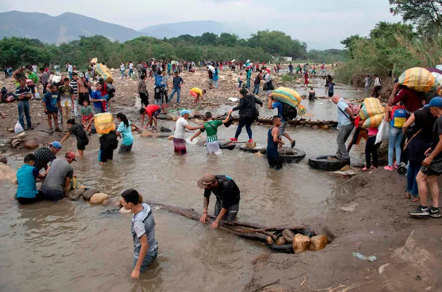 People cross from Cucuta in Colombia back to San Antonio del Tachira in Venezuela after buying goods to resell, through improvised bridged on the “trochas”, illegal trails on the border between the two countries near the Simon Bolivar international bridge, on March 21, 2019. Venezuela is in the grip of a humanitarian crisis due to shortages of food and medicine exacerbated by hyperinflation. (Photo by Juan Pablo Bayona/AFP Photo)