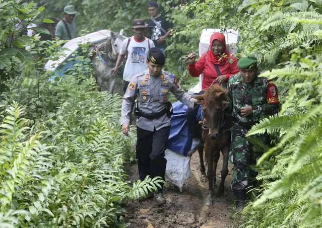 Police officers and soldiers escort electoral workers using horses to distribute ballot boxes and other election paraphernalia to polling stations in remote villages in Tempurejo, East Java, Indonesia, Monday, April 15, 2019. The world's third largest democracy is gearing up to hold its legislative and presidential elections that will pit the incumbent Joko Widodo against his contender former special forces general Prabowo Subianto. (Photo by AP Photo/Trisnadi)