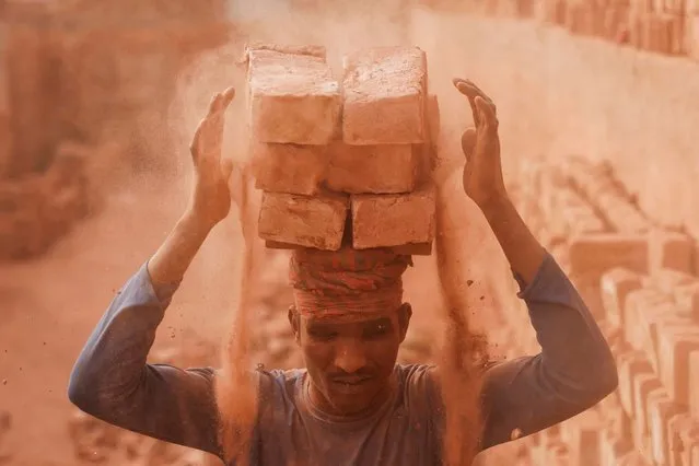 A worker loads bricks on his head in the dusty working environment of a brick factory, as he transports them to another place, in Dhaka, Bangladesh, on January 16, 2024. (Photo by Mohammad Ponir Hossain/Reuters)