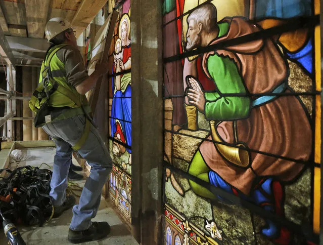 Stained glass foreman Jim Edbrooke lifts a restored stained glass panel in a protective frame for installation in St. Patrick's Cathedral in New York on Wednesday, May 6, 2015. (Photo by Mary Altaffer/AP Photo)