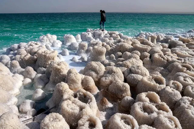 A hiker visits patterns formed by crystalized minerals in the Israeli Kibbutz Ein Gedi area at the shore of the southern part of the Dead Sea, a dried-up sea stretch which exposed and created a salt plain, on December 26, 2020. A spectacular expanse of water in the desert, flanked by cliffs to east and west, the Dead Sea has lost a third of its surface area since 1960. The blue water recedes about a metre (yard) every year, leaving behind a lunar landscape whitened by salt and perforated with gaping holes. (Photo by Menahem Kahana/AFP Photo)
