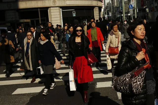 People cross a street in the shopping district of Ginza in Tokyo, Japan, February 4, 2016. (Photo by Thomas Peter/Reuters)