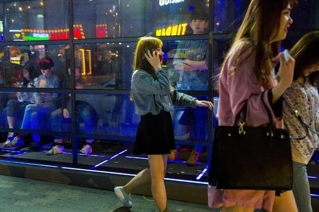 Women walks past a club in the trendy nightlife district of Hongdae in Seoul, May 9, 2015. (Photo by Thomas Peter/Reuters)