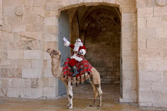 A Palestinian man dressed as Santa Claus gestures as he rides a camel in Jerusalem's Old City during Christmas celebrations, on December 23, 2021. (Photo by Ahmad Gharabli/AFP Photo)
