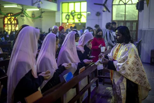Indian Christians receive the holy communion from a priest after attending a Christmas mass at Saint Mary's church in Noida, a suburb of New Delhi, India, Saturday, December 25, 2021. (Photo by Altaf Qadri/AP Photo)