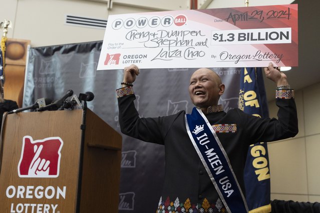 Cheng “Charlie” Saephan holds display check above his head after speaking during a news conference where it was revealed that he was one of the winners of the $1.3 billion Powerball jackpot at the Oregon Lottery headquarters on Monday, April 29, 2024, in Salem, Ore. (Photo by Jenny Kane/AP Photo)