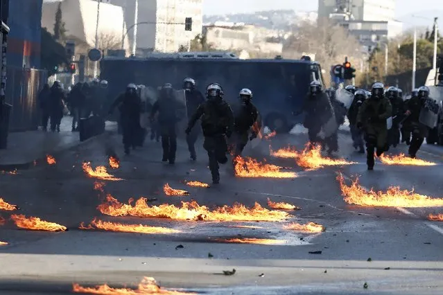 Riot policemen run through flames from petrol bombs during a rally in the northern Greek city of Thessaloniki, Greece, on Saturday, January 15, 2022. (Photo by Giannis Papanikos/AP Photo)