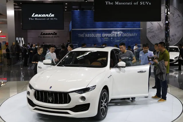 Invited guests examine the new Maserati Levante SUV after it was unveiled at the Beijing International Automotive Exhibition in Beijing, Monday, April 25, 2016. (Photo by Andy Wong/AP Photo)