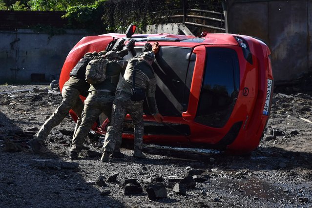Ukrainian servicemen turn over a damaged car at the scene of a Russian missile attack in Zaporizhzhia, Ukraine, Wednesday, May 8, 2024. (Photo by Andriy Andriyenko/AP Photo)