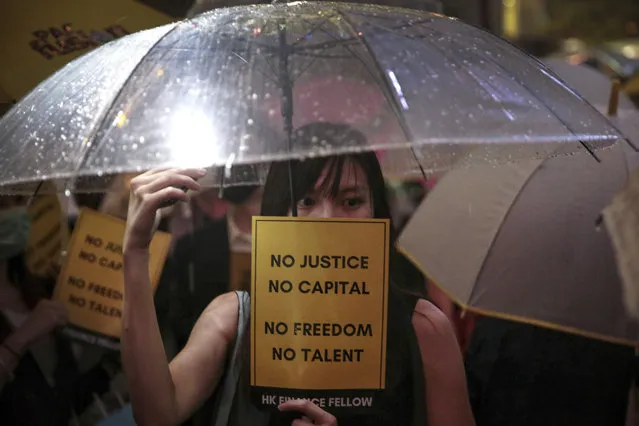 A woman holds an umbrella and a placard as people gather at Chater Garden to give support to the recent protests against the extradition bill, at the financial district in Hong Kong, Thursday, August 1, 2019. The Chinese army has released a promotional video for its Hong Kong-based troops at a time of uncertainty over whether the military will intervene in the city's summer of protest. (Photo by Elson Li/HK01 via AP Photo)