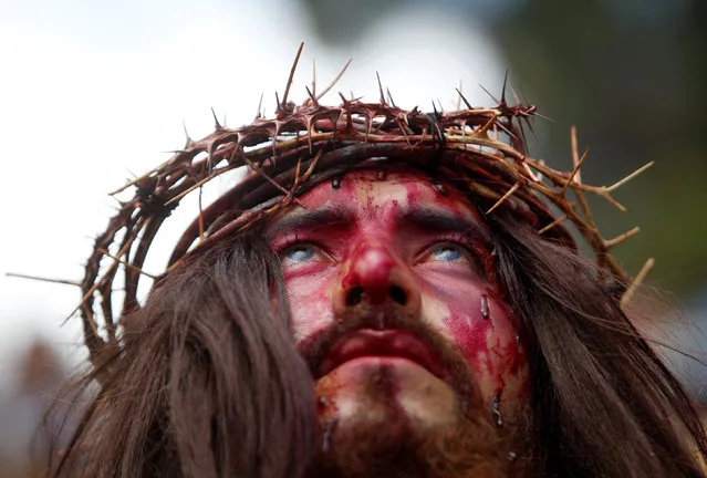 Jesus Christ, played by local resident Tomas Izaguirre, looks up during a Via Crucis representation on Good Friday in Tegucigalpa, Honduras April 14, 2017. (Photo by Jorge Cabrera/Reuters)