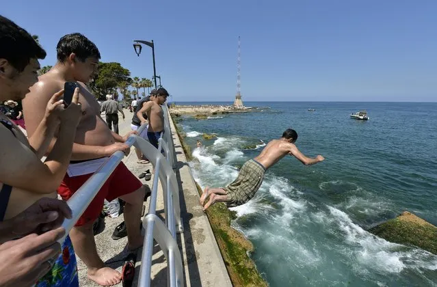 A youth jumps into the Mediterranean sea while others watch him at Manara's seaside in Beirut, Lebanon, 27 April 2014. Lebanese are going to the beach to cool off as summer weather begins in the region. (Photo by Wael Hamzeh/EPA)