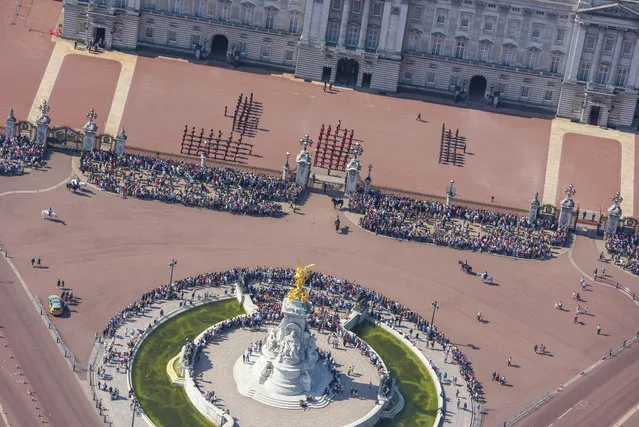 The Guard and tourists at Buckingham Palace and Victoria Memorial. (Photo by Jason Hawkes/Caters News Agency)