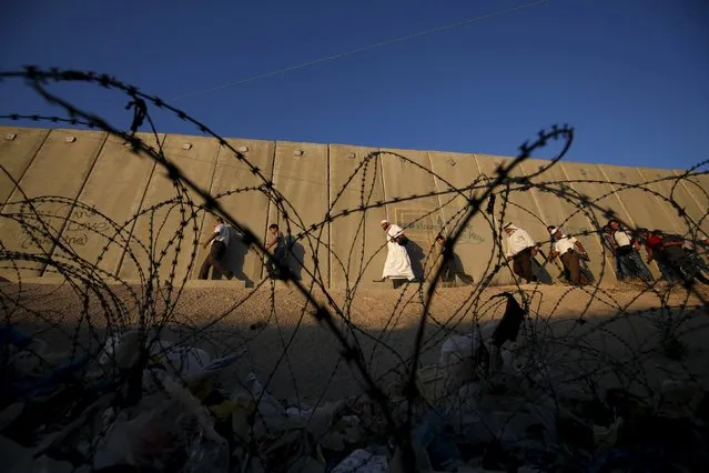 Palestinians walk past Israel's controversial barrier as they make their way to attend the fourth Friday prayer of Ramadan in Jerusalem's al-Aqsa mosque, at Qalandia checkpoint near the West Bank city of Ramallah July 10, 2015. (Photo by Mohamad Torokman/Reuters)
