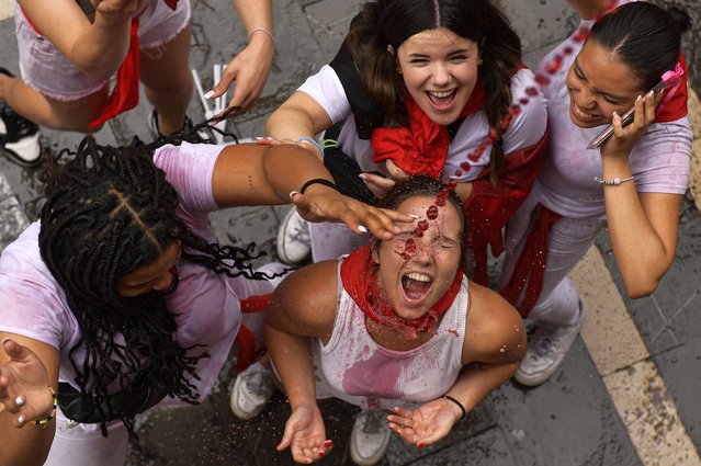 A reveler drinks wine as she attends the official start of nine days of uninterrupted partying in Pamplona's famed running-of-the-bulls festival in Pamplona, Spain, Saturday, July 6, 2024. (Photo by Alvaro Barrientos/AP Photo)