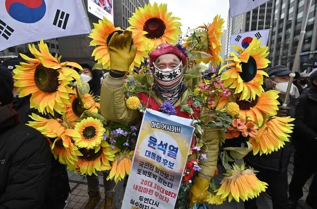 A man decorated with plastic flowers supports South Korean presidential candidate Yoon Suk-yeol of the opposition People Power Party during an election campaign in downtown Seoul on February 15, 2022, as the official presidential campaign period kicked off for a 22-day run ahead of the election on March 9. (Photo by Jung Yeon-je/AFP Photo)