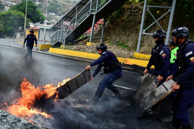 Riot police remove a barricade with fire following clashes with protesters during a road blockade against the election results in Caracas, Venezuela on July 29, 2024. (Photo by Maxwell Briceno/Reuters)