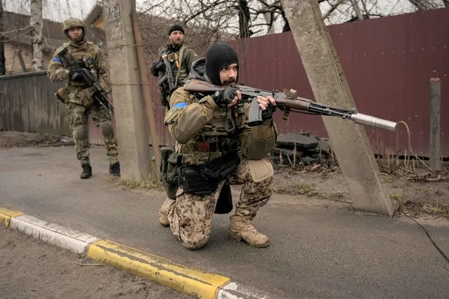 A Ukrainian serviceman secures the retreat of fellow soldiers who checked bodies lying on the street for booby traps in the formerly Russian-occupied Kyiv suburb of Bucha, Ukraine, Saturday, April 2, 2022. (Photo by Rodrigo Abd/AP Photo)