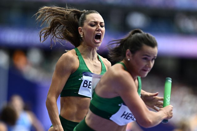 Ireland's Sophie Becker passes the baton to Ireland's Phil Healy in the women's 4x400m relay heat of the athletics event at the Paris 2024 Olympic Games at Stade de France in Saint-Denis, north of Paris, on August 9, 2024. (Photo by Jewel Samad/AFP Photo)