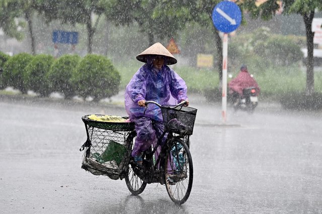 A woman cycles in a heavy downpour in Hanoi on July 16, 2024. (Photo by Nhac Nguyen/AFP Photo)