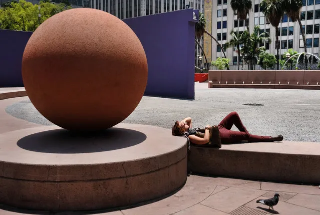 A woman suns herself in an empty park in downtown Los Angeles on Friday, June 3, 2016. A heat wave in large parts of the West and Southwest has many scattering for reprieve from the sun. (Photo by Richard Vogel/AP Photo)