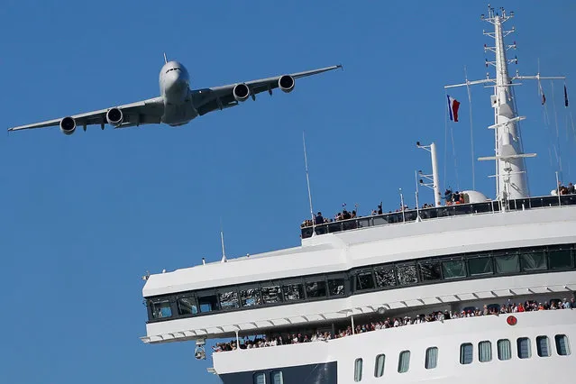 An Airbus A380, the world's largest jetliner, flies over the Queen Mary 2 ocean liner as it takes the start of The Bridge 2017, a transatlantic race against Ultim trimarans from Saint-Nazaire to New-York, in Saint-Nazaire, France June 25, 2017. (Photo by Stephane Mahe/Reuters)