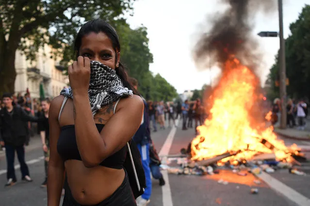 A woman covers her face as a fire burns in the middle of town during an anti-G20 protest on July 7, 2017 in Hamburg, Germany. Authorities are braced for large-scale and disruptive protests as Leaders of the G20 group of nations arrive in Hamburg for the July 7-8 G20 summit. (Photo by Leon Neal/Getty Images)