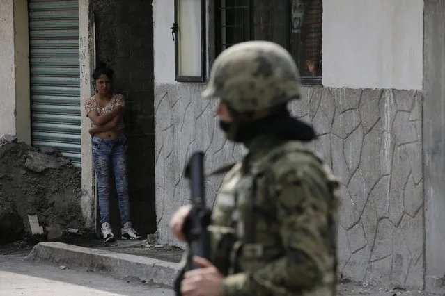A woman peers out from a home as Marines block off the area where the suspected leader of a drug gang and seven others were killed, according to the Navy, in southern Mexico City, Thursday, July 20, 2017. In a statement Thursday, the Navy said a gang of street-level drug dealers operated in the Tlahuac and Iztapalapa districts on the city's south and east sides, where it dealt drugs, as well as carried out kidnappings, extortion and murder. (Photo by Rebecca Blackwell/AP Photo)