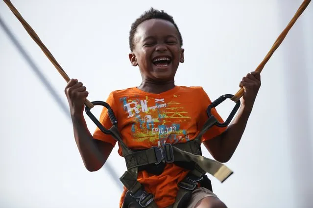 Dominic Bennett,6,  bounces on the bungee trampoline during AthFest in Athens, Ga.,Friday, June 24, 2016. The AthFest music festival is a production of AthFest Educates, a nonprofit music and arts education organization in Athens. (Photo by John Roark/Athens Banner-Herald via AP Photo)