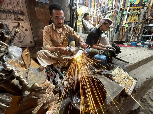 A craftsman grinds the blade of a traditional dagger, known as Jambiya, outside a shop in Sanaa, Yemen on May 23, 2022. (Photo by Khaled Abdullah/Reuters)