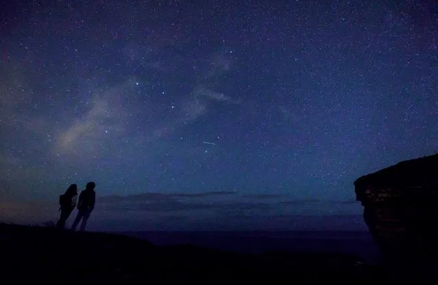 This picture taken on August 12, 2017 shows a couple enjoying Perseid meteor along the Milky Way illuminating the dark sky near Comillas, Cantabria community, northern Spain, during the “Perseids” meteor shower. Northern hemisphere sky-gazers are in for a special treat on August 11 and 13, night with a rare shooting star “outburst”, which astronomers hope will not be marred by clouds and a bright Moon. (Photo by Cesar Manso/AFP Photo)