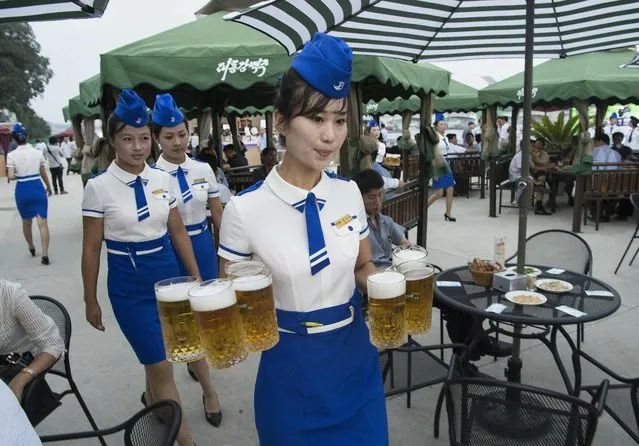 This photo taken on August 12, 2016 shows a waitress carrying jugs of beer to guests before the opening of the Pyongyang Taedonggang Beer Festival on the banks of the Taedong river in Pyongyang. (Photo by Kim Won- Jin/AFP Photo)