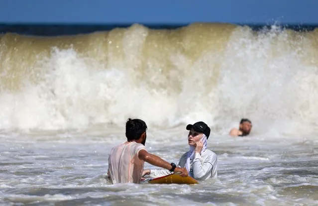 Sabah Abu Ghanem, a 22-year-old Palestinian surfer, trains with her brother off the shore of Gaza City, on June 13, 2022. (Photo by Mohammed Abed/AFP Photo)