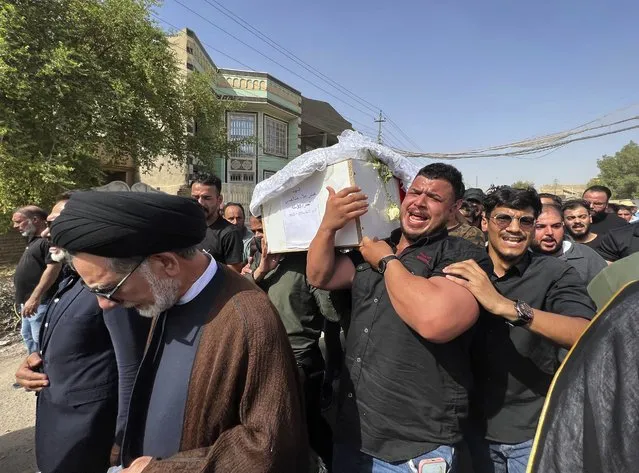 The coffin carrying Abbas Abdul Hussein, a 30-year-old victim of an artillery strike, is received by his family in Baghdad, to later lay him to rest in Najaf city, Thursday, July 21, 2022, in Baghdad, Iraq. Hussein was on his honeymoon, five days after his wedding, when at least four artillery shells struck the resort area of Barakh in the Zakho district in the Iraqi semi-autonomous Kurdish-run region, killing nine people. (Photo by Ali Jabar/AP Photo)