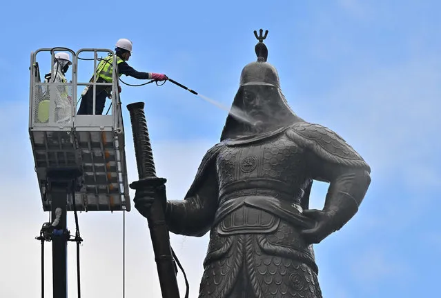 A South Korean worker sprays water to wash the bronze statue of Admiral Yi Sun-shin, who won a major naval victory over Japan in the 16th century, during a clean-up event at Gwanghwamun square in Seoul on July 21, 2022. (Photo by Jung Yeon-je/AFP Photo)