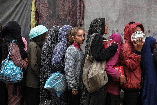 Palestinians gather to receive food cooked by a charity kitchen amid a hunger crisis as the Israel-Gaza conflict continues in Deir el-Balah, Central Gaza Strip, on December 20, 2024. (Photo by APA Images/Rex Features/Shutterstock)