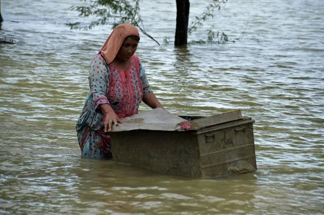 A woman uses a trunk to salvage usable items from her flood-hit home in Jaffarabad, a district of Pakistan's southwestern Baluchistan province, Thursday, August 25, 2022. Pakistan's government in an overnight appeal sought relief assistance from the international community for flood-affected people in this impoverished Islamic nation, as the exceptionally heavier monsoon rain in recent decades continued lashing various parts of the country. (Photo by Zahid Hussain/AP Photo)