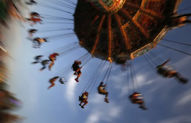 People ride on a swing at the Wisconsin State Fair in West Allis, Wisconsin, August 9, 2014. The fair started over 150 years ago and mixes agricultural exhibits with amusements rides. (Photo by Jim Young/Reuters)