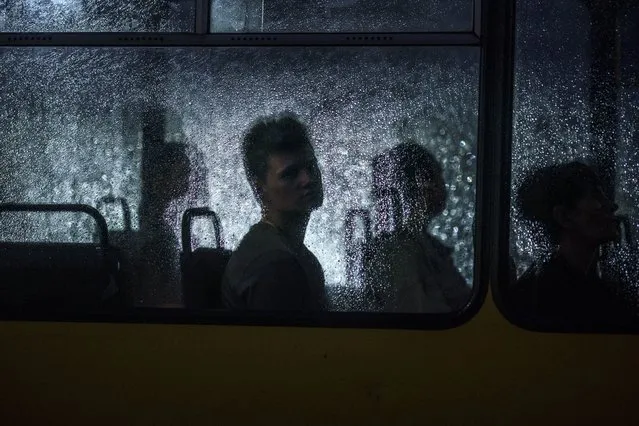 A passenger looks out of a city bus window during a rain shower in Dnipro, Ukraine, Monday, August 1, 2022. (Photo by David Goldman/AP Photo)