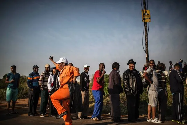 A South African municipal worker dances as voters queue at a polling station outside the hostels in Umlazi, Durban, on August 3, 2016. South Africans voted in closely-contested municipal elections that could deal a heavy blow to the African National Congress (ANC), which has ruled since leading the struggle to end apartheid. Nelson Mandela's former party risks losing control of key cities including the capital Pretoria, the economic hub Johannesburg and coastal Port Elizabeth, according to some polls. (Photo by Marco Longari/AFP Photo)