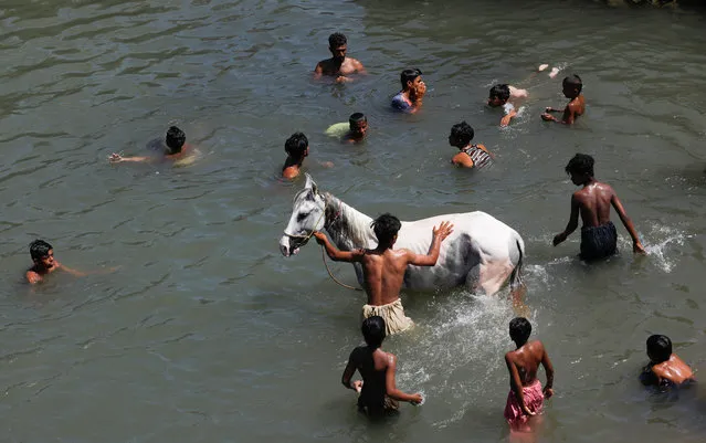 A man bathes his horse as people cool off in Arabian Sea during the Muslim's fasting month of Ramadan, amid lockdown in efforts to stop the spread of the coronavirus disease (COVID-19), on the outskirts of Karachi, Pakistan on April 29, 2020. (Photo by Akhtar Soomro/Reuters)