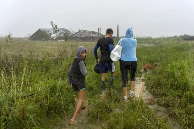 A family walks through the rain in search of shelter after their home flooded when Hurricane Ian hit in Pinar del Rio, Cuba, Tuesday, September 27, 2022. (Photo by Ramon Espinosa/AP Photo)