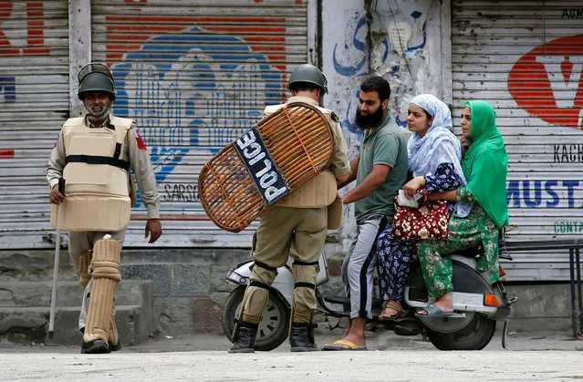 An Indian policeman checks the identification cards of a family during a curfew in Srinagar, August 8, 2016. (Photo by Danish Ismail/Reuters)